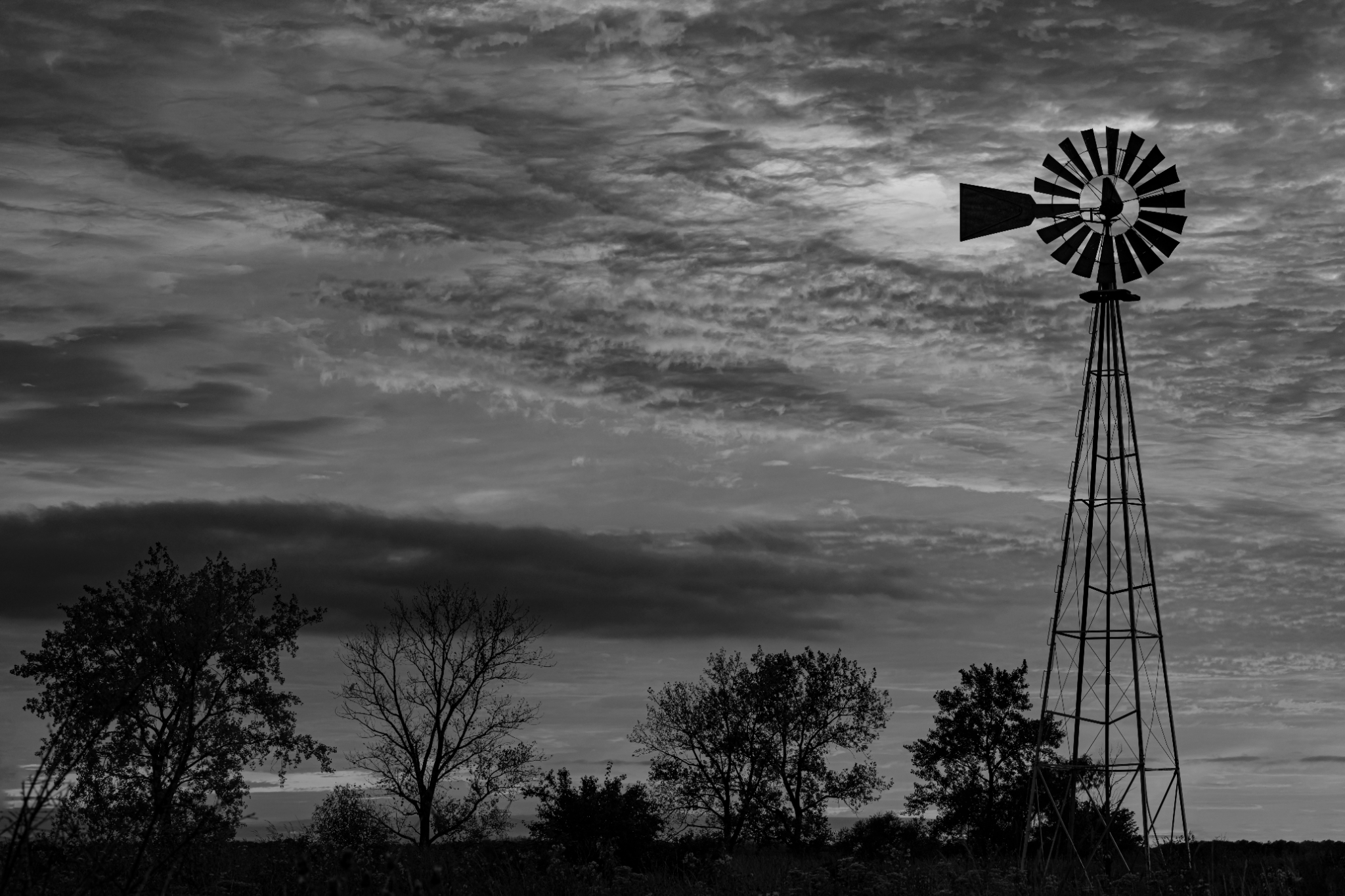 A windmill on the Illinois prairie beneath dark storm clouds
